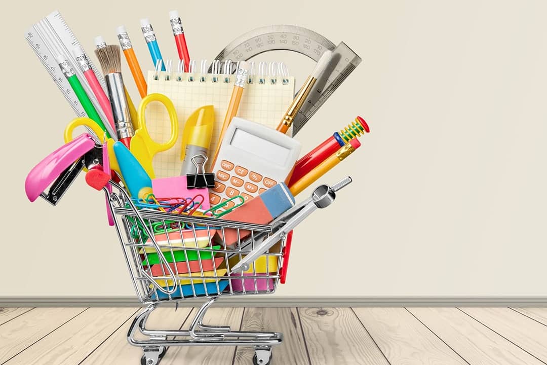 A mini shopping cart filled with different school materials and supplies.